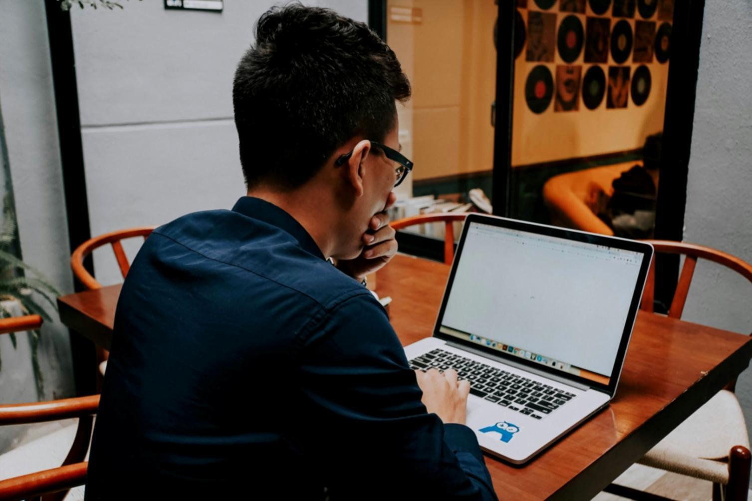 Estudiante trabajando desde casa con laptop y documentos financieros